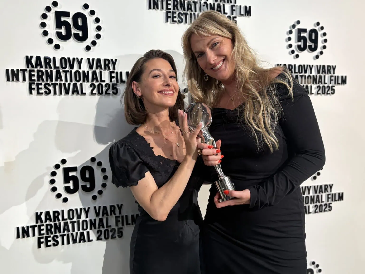 Picture: Two happy women holding award in front of poster