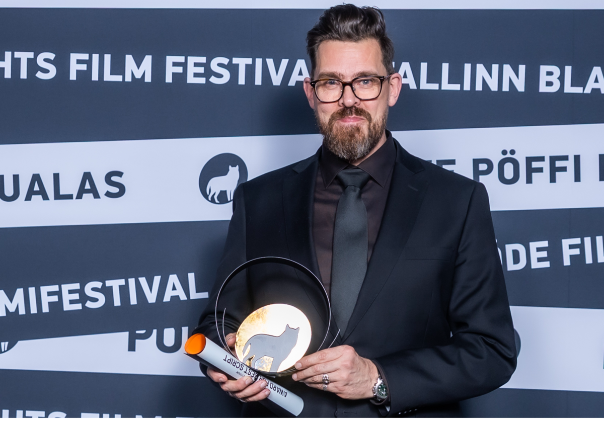 Foto. Mann i mørk dress holder pris.