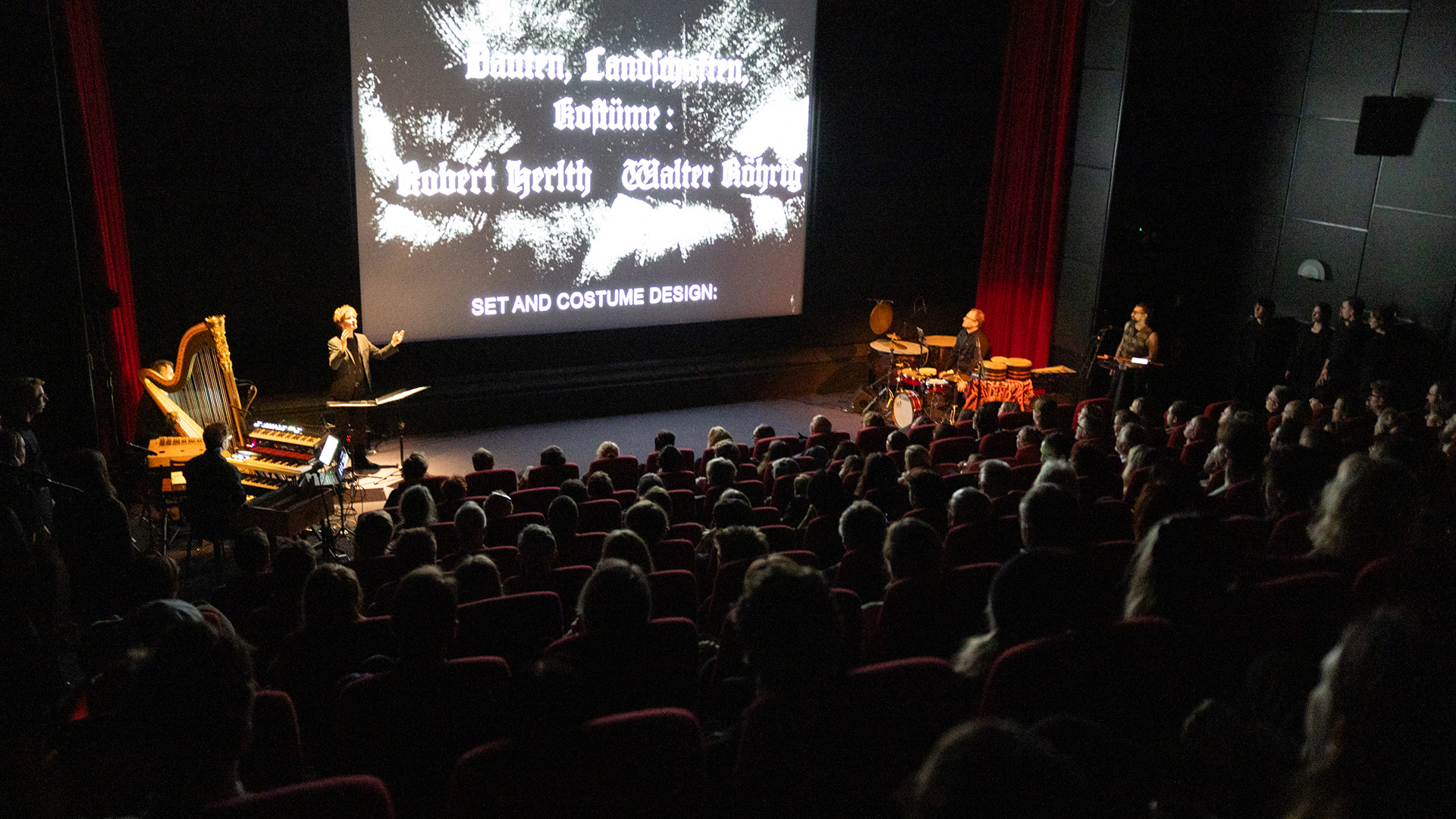 Foto. Full kinosal med musikere foran lerretet.