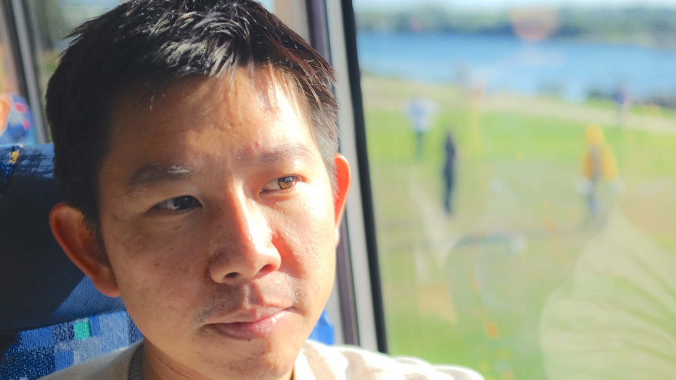 Foto. Portrett av asiatisk mann ved et vindu.