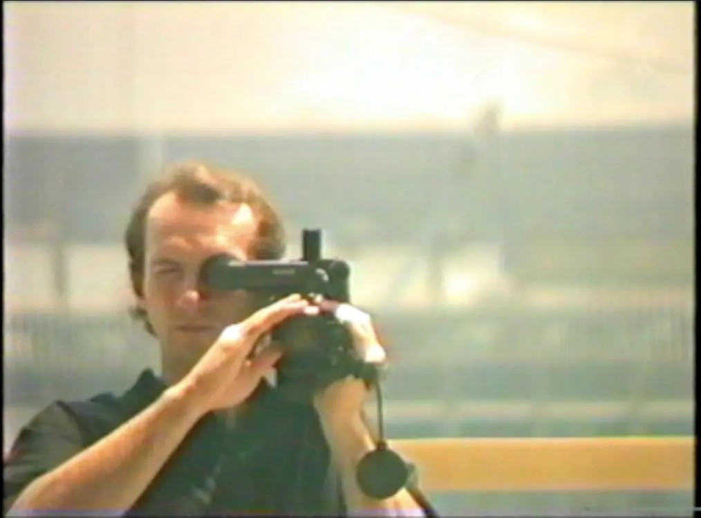foto. kornete stillbilde fra hjemmevideo av mann som filmer med videokamera i et speil