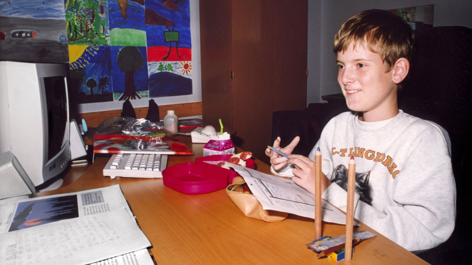 foto. en gutt sitter i høyre til bildet og spiller dataspill mens han ser på skjermen til venstre i bildet.