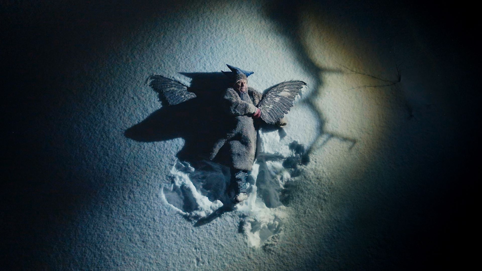 Foto. En person lagger en engel i snøen.