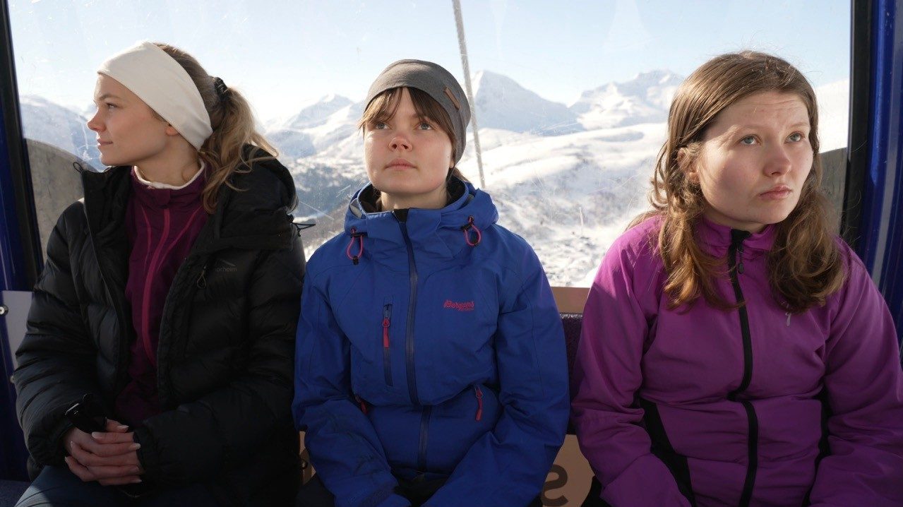 Foto. Tre kvinner ser i hver sin retning med fjell i bakgrunnen