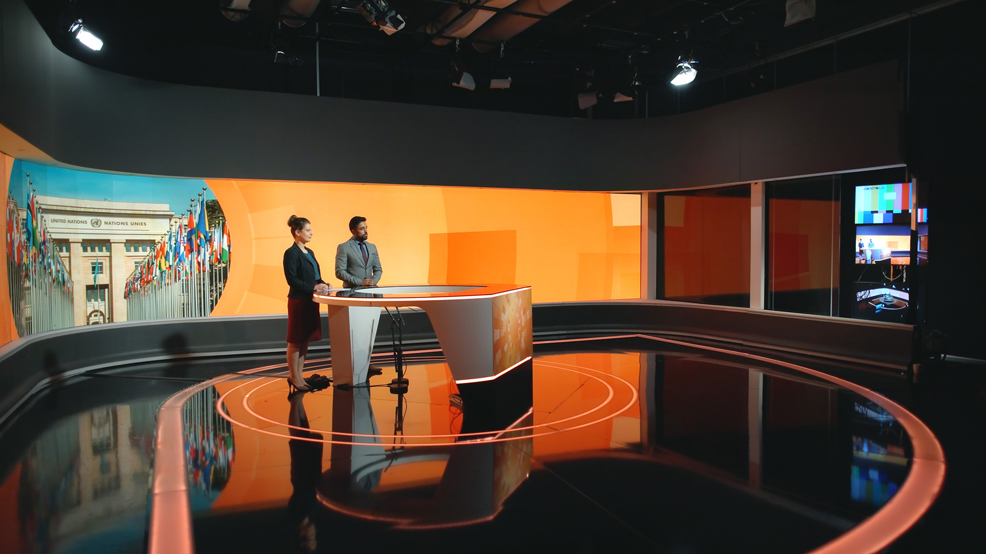 foto. to personer står bak en pult i et tv-studio.