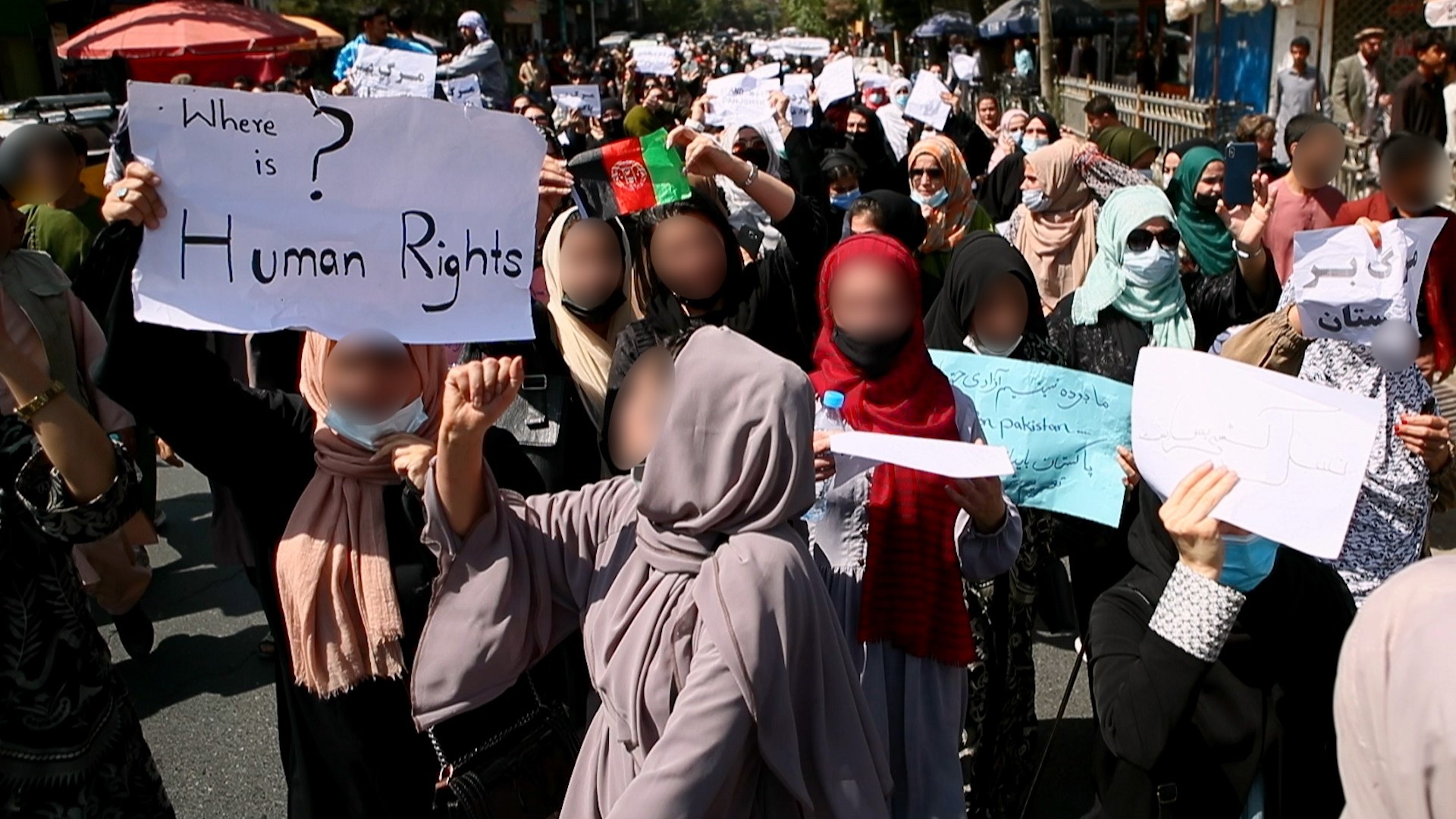 Foto. En gruppe kvinner i hijab står ute og protesterer, mange av ansiktene er gjort uskapre.