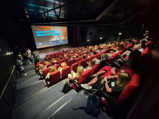 Foto. Fullsatt kinosal med røde seter sett fra bakerst i salen mot lerretet.