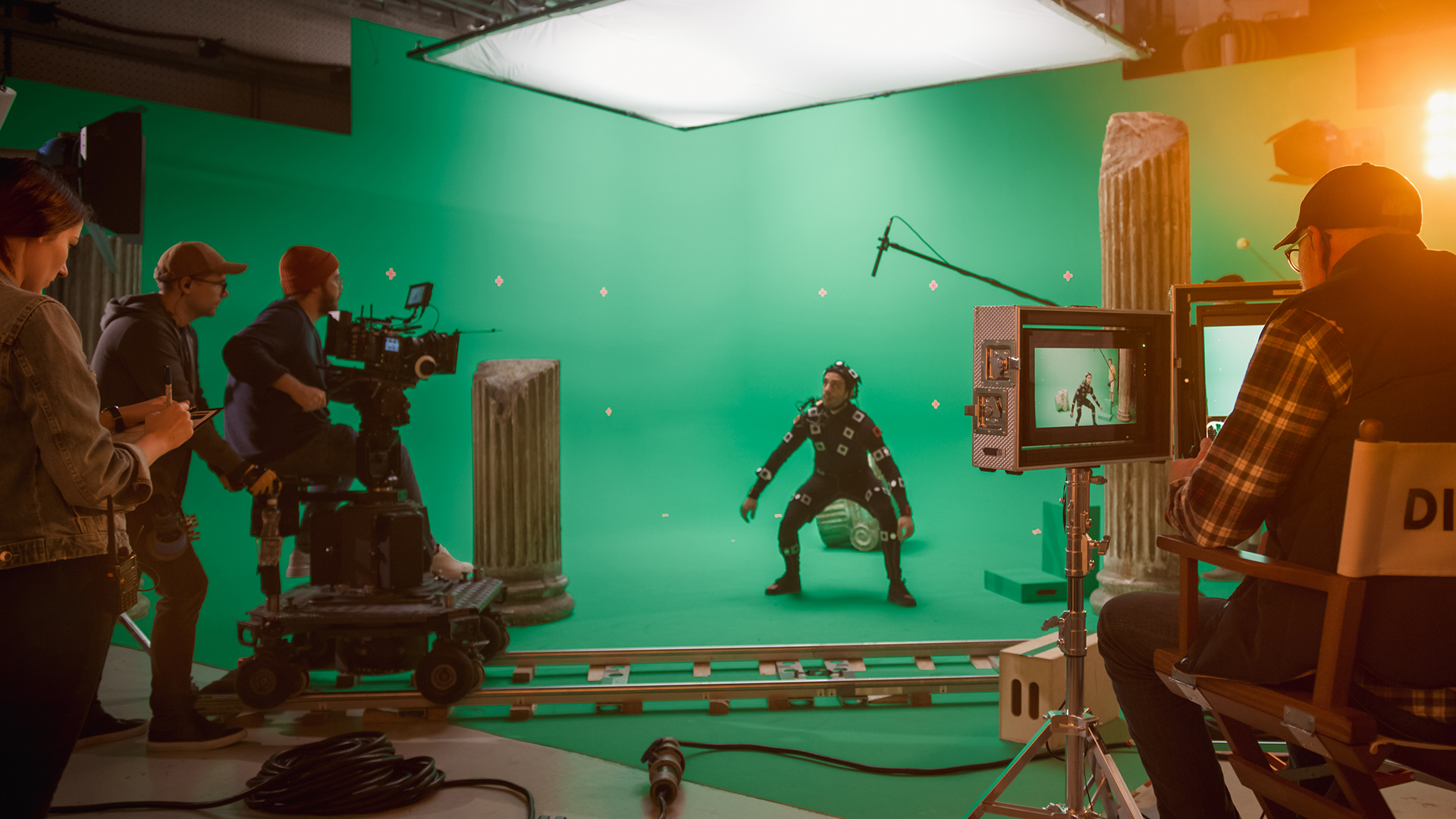 Foto. Viser en et filmstudio hvor en mann står foran en en grønn skjerm  med elektroder på kroppen mens han filmes.