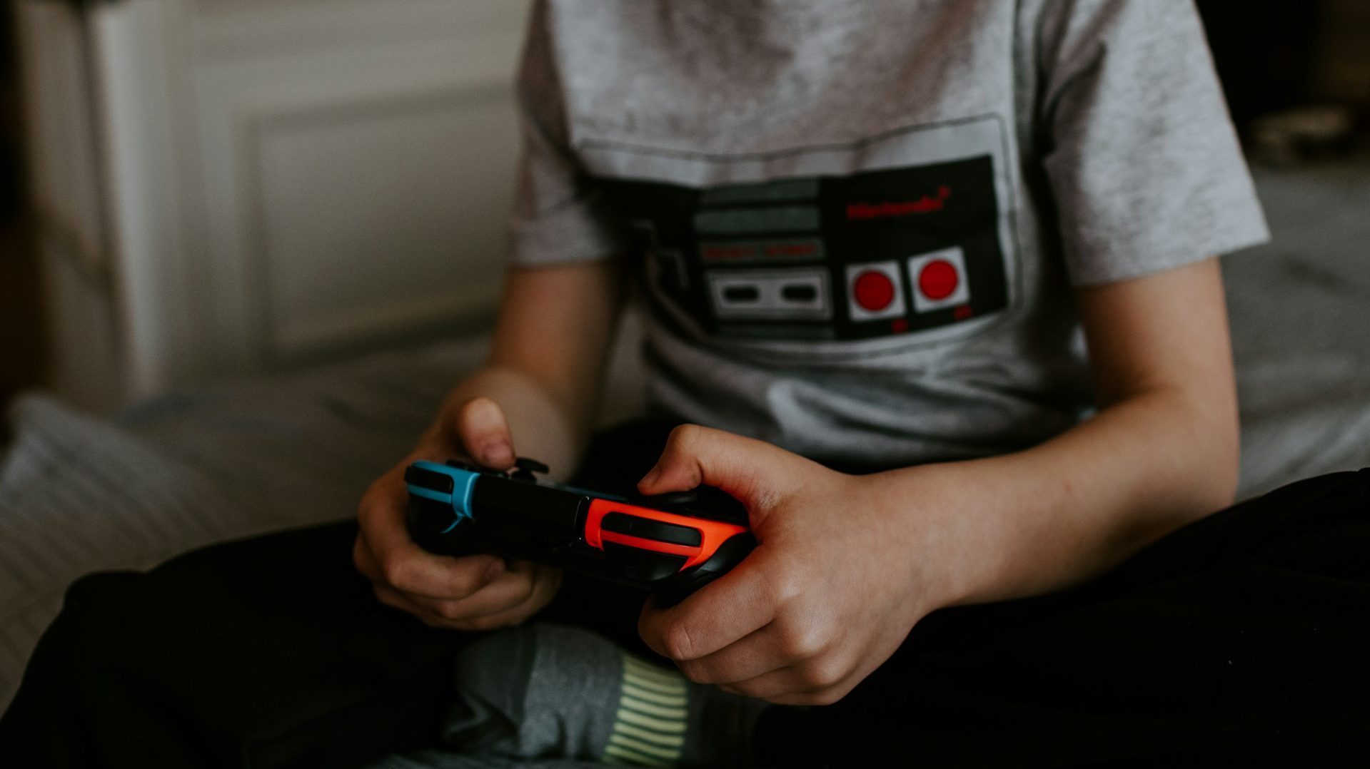 En ung gutt i grå t-skjorte spiller Nintendo Switch.