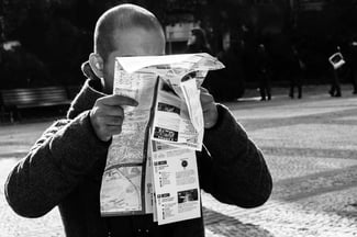 black and white photo of man consulting unfolded map up close