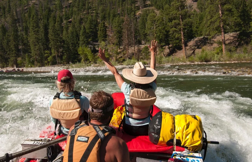 Woman raises arms in raft on Middle Fork of the Salmon River, Idaho