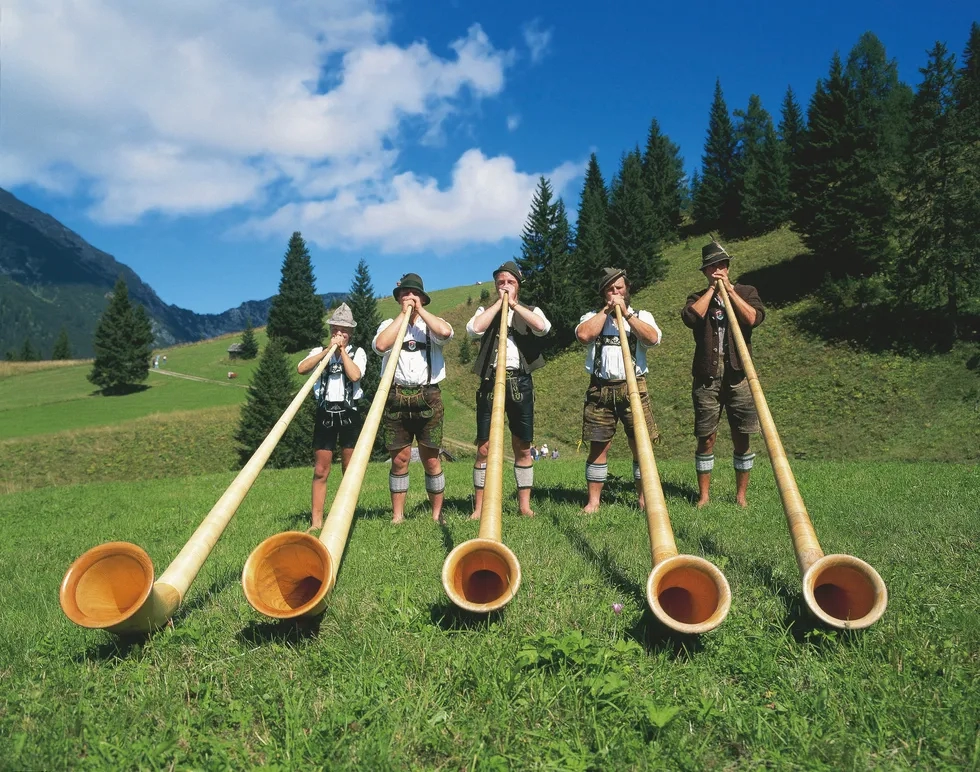 Ausrian musicians in the alps playing huge horns.