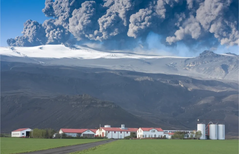 Eyjafjallajökull volcano erupting in back of village, Iceland