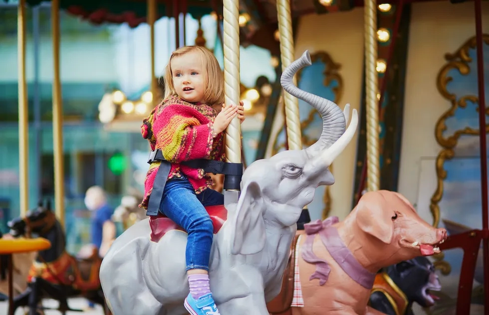 child having fun on vintage merry-go-round in Paris