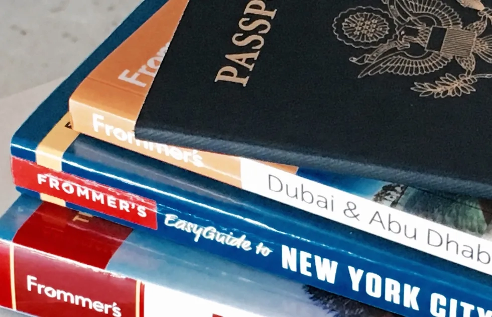 A United States passport on top of a stack of Frommer's travel guides