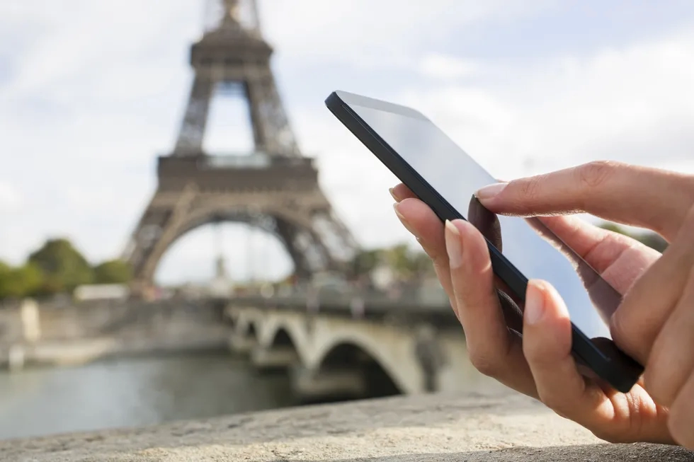 Using a cell phone in front of the Eiffel Tower in Paris