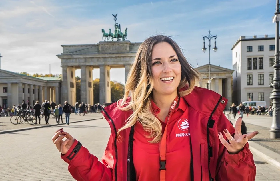 A tour guide with Sandeman's New Europe explains the importance of the Brandenburg Gate in Berlin