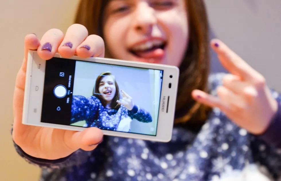 A young woman mugs for her phone as she snaps a selfie