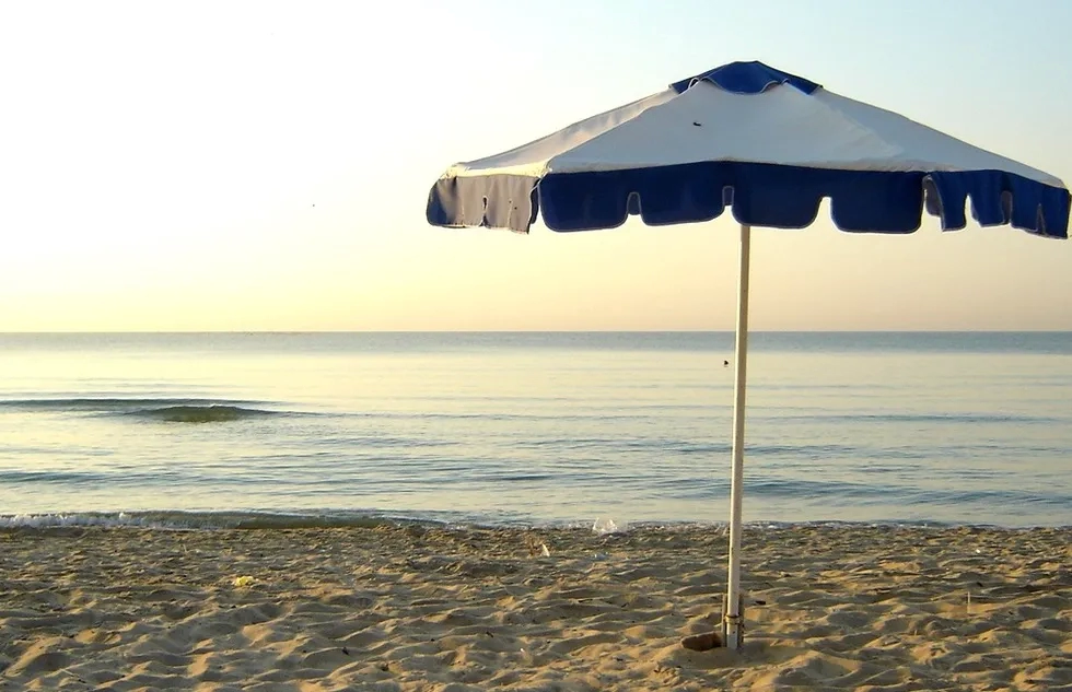 A lone beach umbrella stands beside the sea