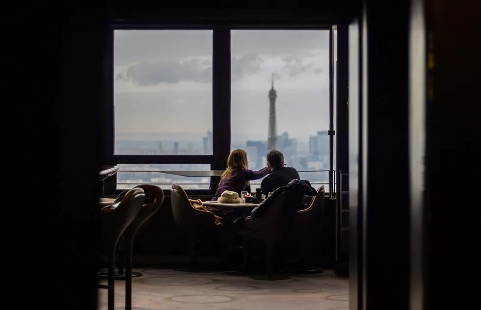 couple looking out window toward Eiffel Tower