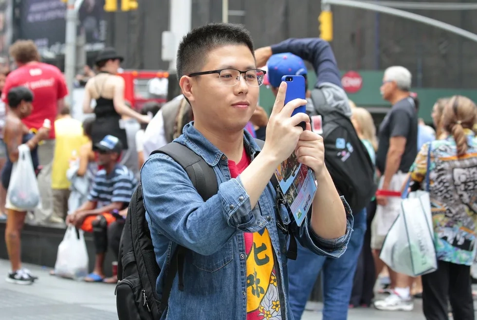 Asian tourist taking smartphone photo in Times Square