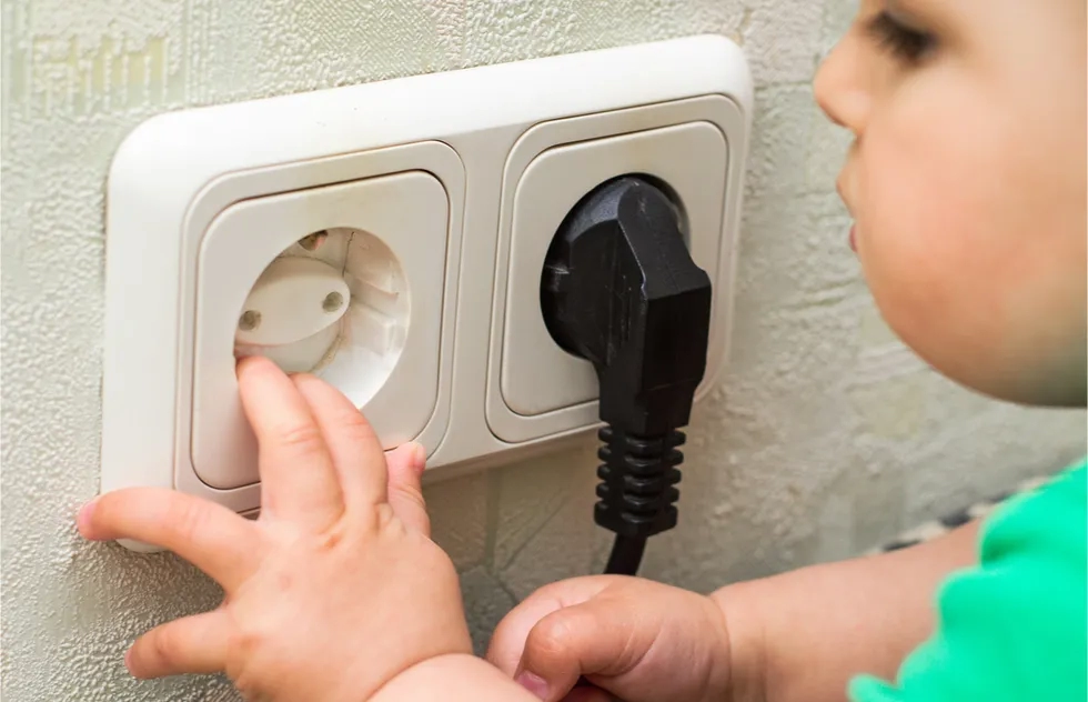 Baby fingers in international power outlet with safety plug