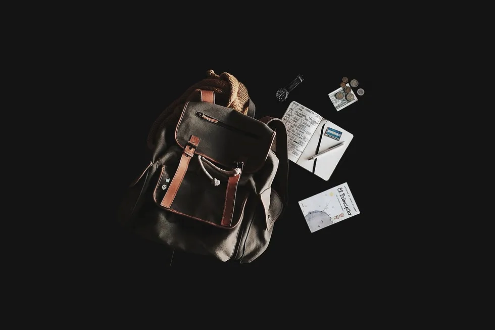 Backpack, passport, money on black background