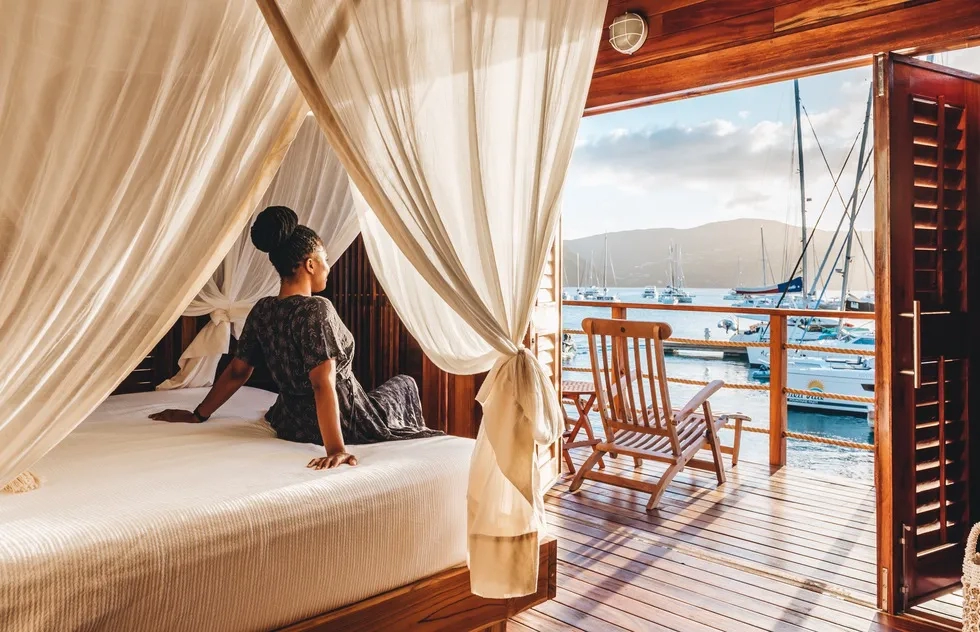 woman sitting on bed in cabin at Bitter End Yacht Club, Virgin Gorda, British Virgin Islands (2022)