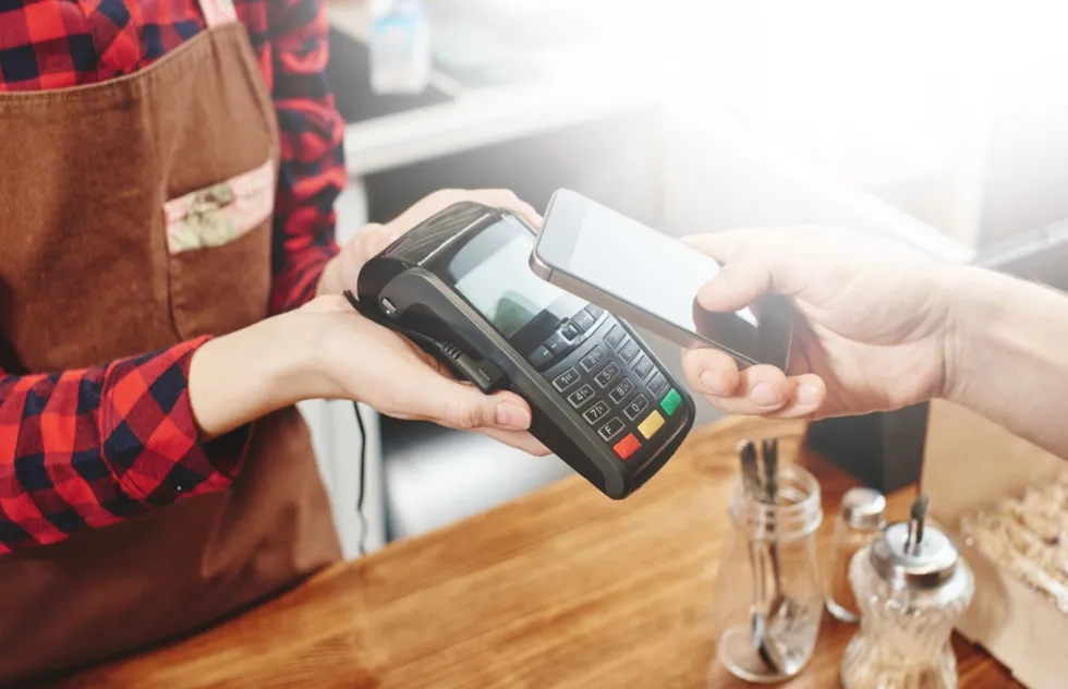 customer taps credit card on handheld credit card machine