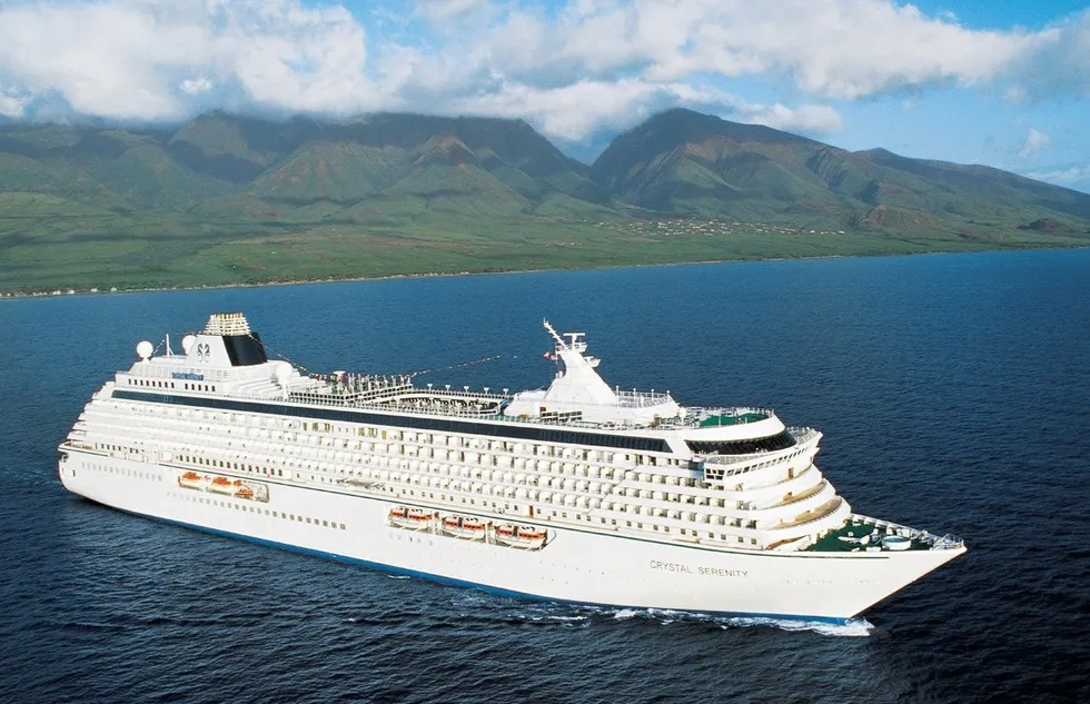 Crystal Serenity sailing off a rugged green coastline