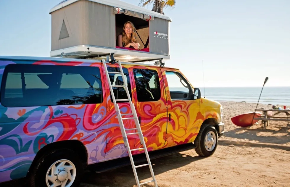 Escape Campervan at beach, woman in tent atop van room