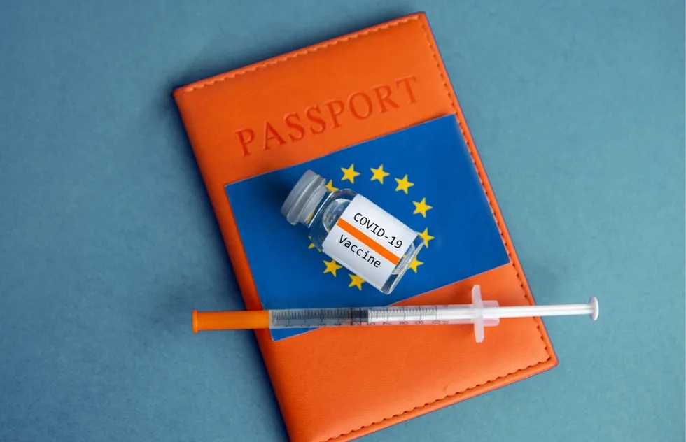 photo illustration: EU passport cover, Covid-19 vaccine and syringe