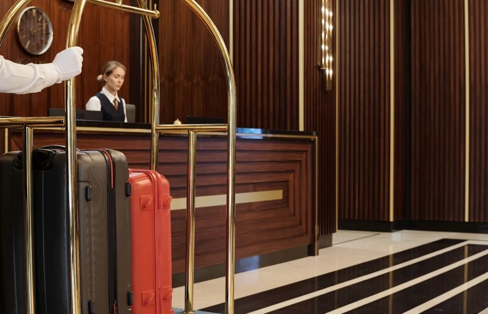 Hotel desk clerk behind luggage cart