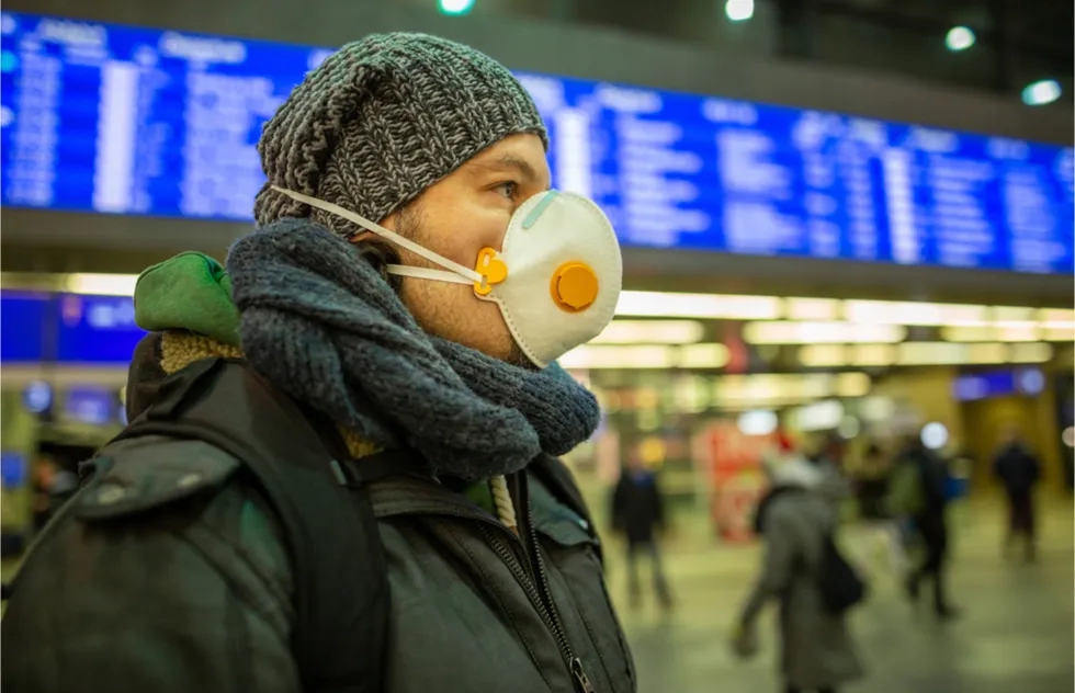 Man wearing mask at airport information board