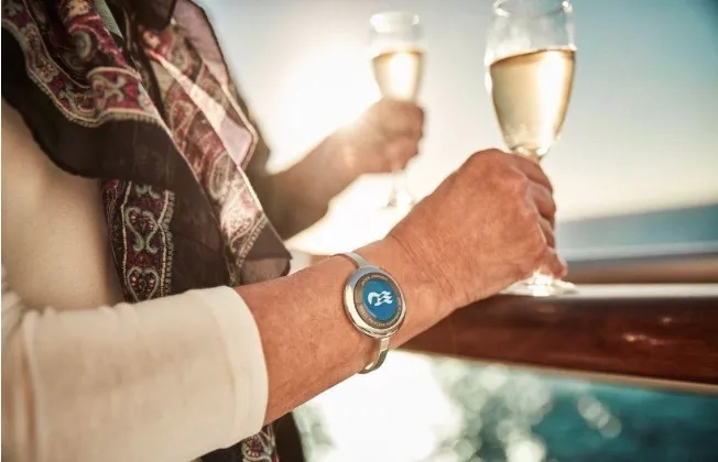 Carnival Corp Ocean Medallion tracking device on champange-drinking passenger