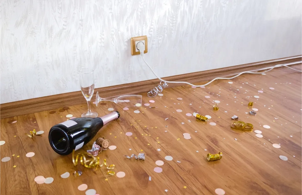 messy leftover from party: champagne bottle, confetti, streamers on floor