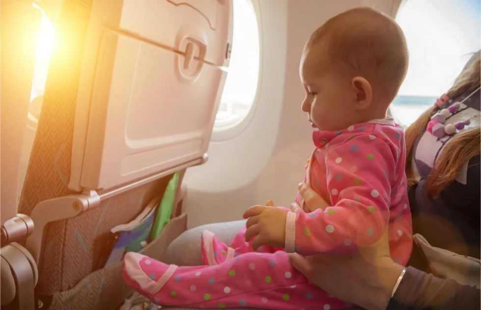 Infant sitting on mother's lap on airplane at sunset or sunrise