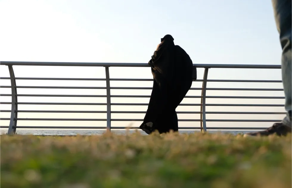 covered woman look at sea over railing in Jeddah, Saudi Arabia