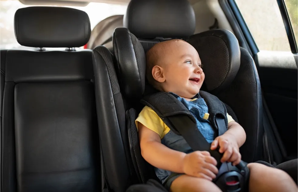 cute laughing baby in a back seat car seat