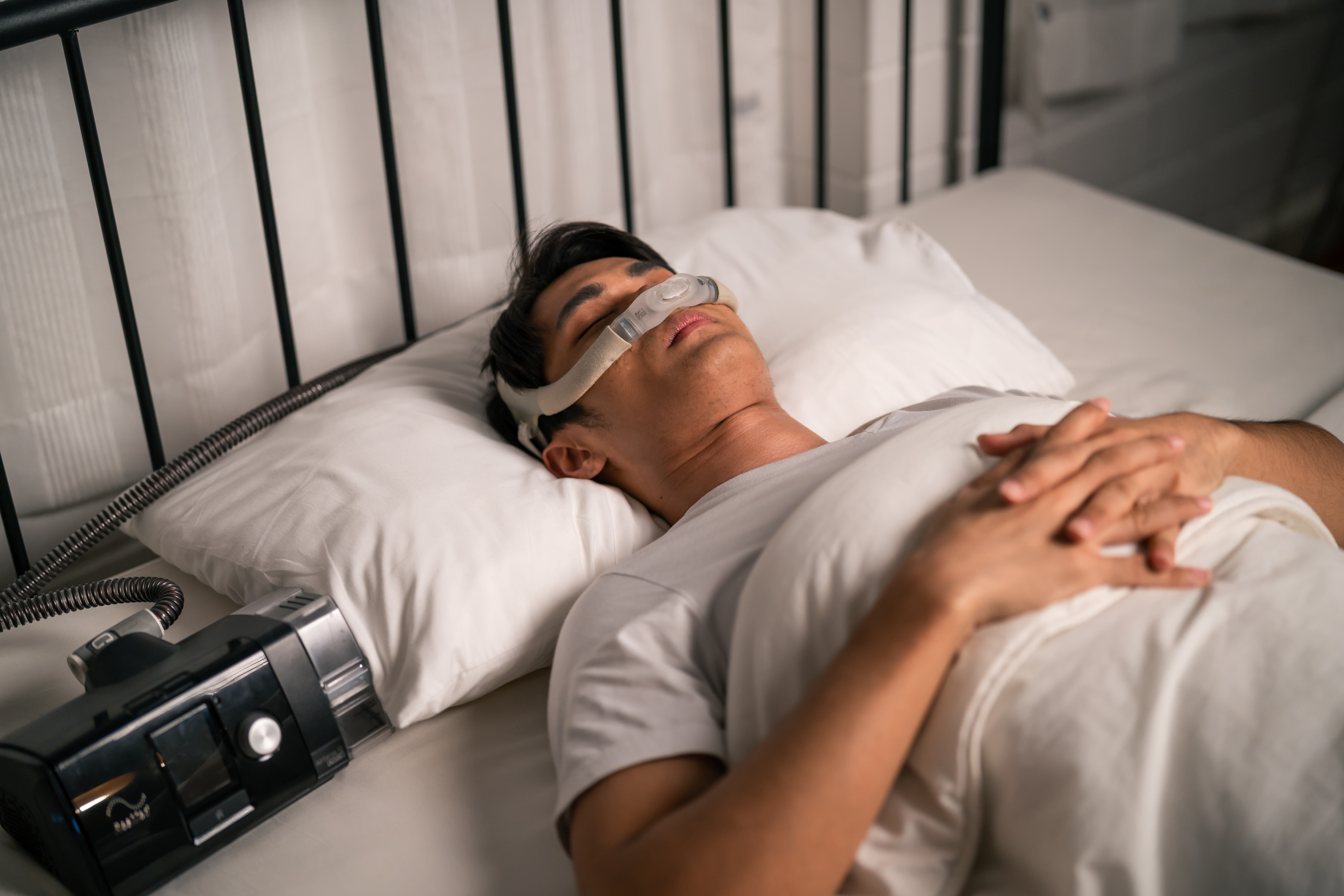 Man wearing cpap machine sleeping smoothly all night in bedroom.