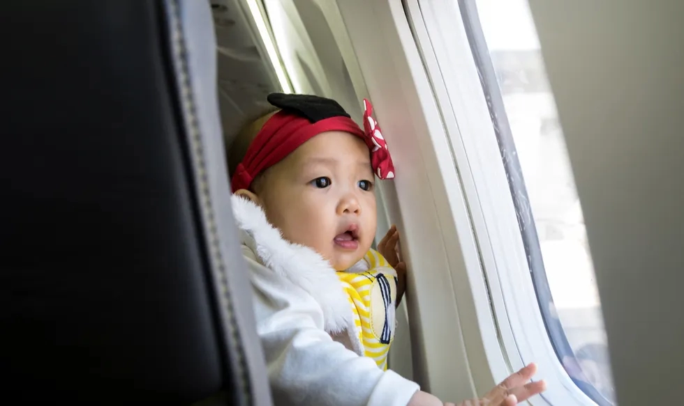 Baby looking out of airplane window with wonder