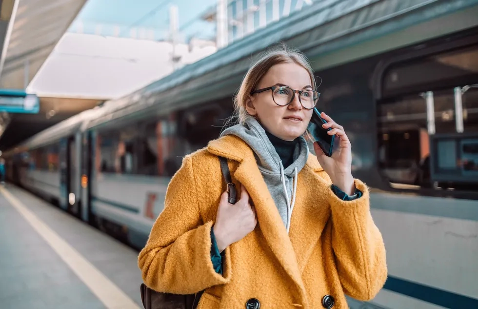 woman using smartphone while walking on railway station platform