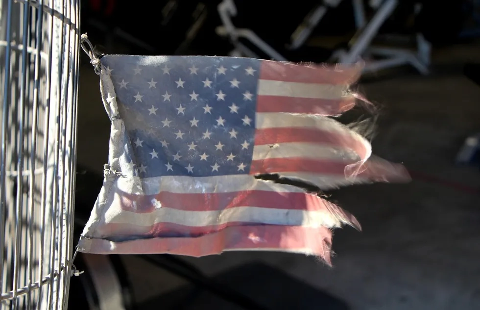 tattered and faded United States flag flying on chain link fence