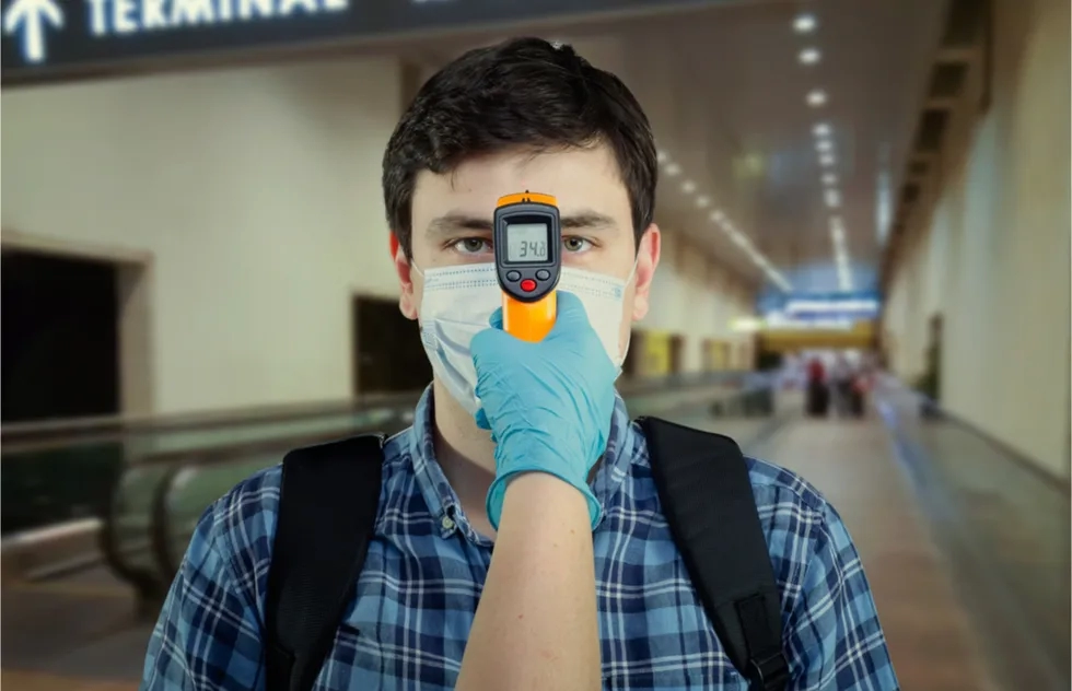 annoyed man gets temperature wand check in airport terminal