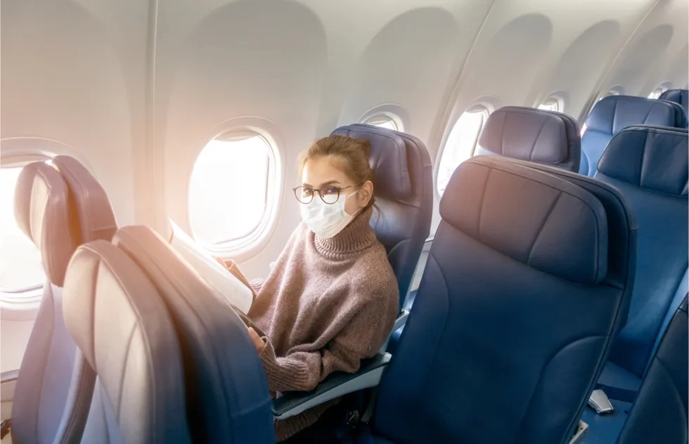 solo woman seating in airline economy wearing mask