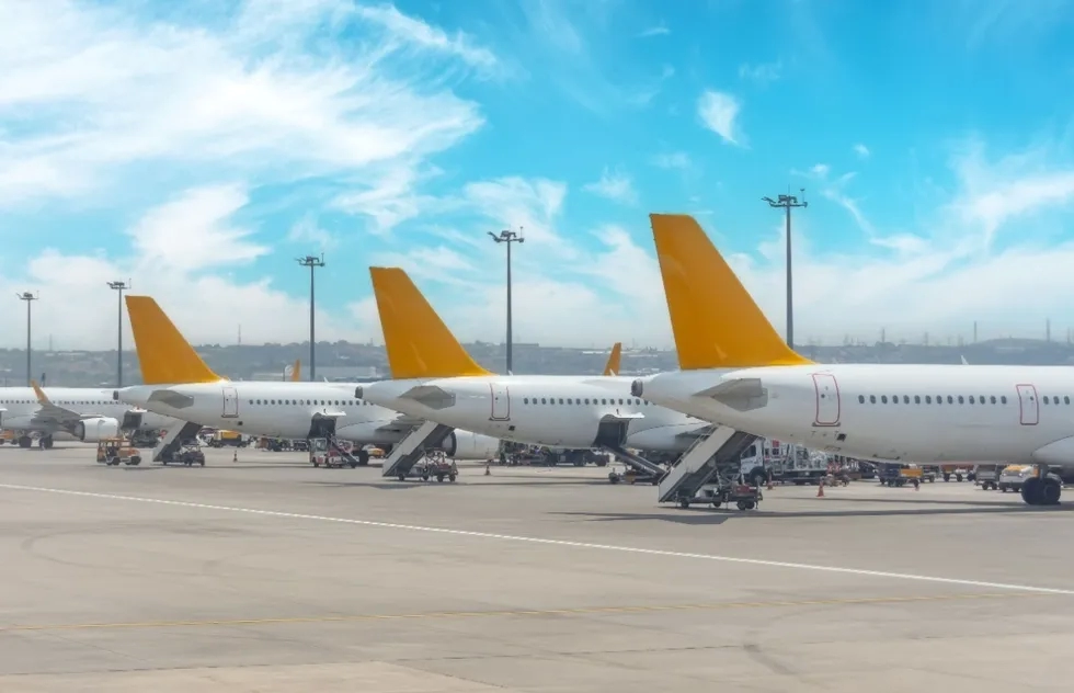 three yellow airplane tail fins at airport gates