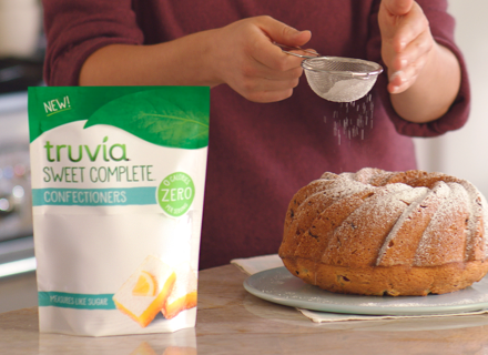 woman sifting and shaking Truvia confectioners sweetener on a bundt cake