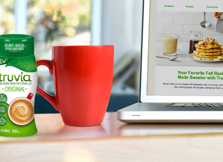 Closeup of Truvia organic liquids bottle sitting next to a red mug and a laptop computer