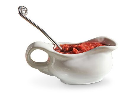 Fresh rhubarb sauce and a serving ladle in a white gravy boat
