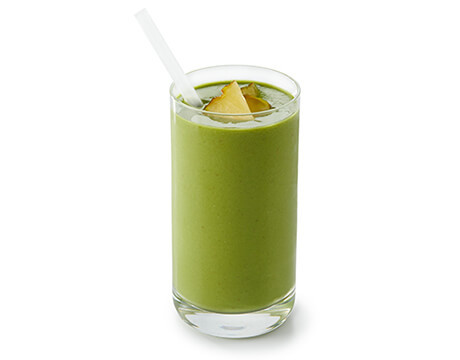 Leafy Green Tropical Smoothie in a clear glass with a straw
